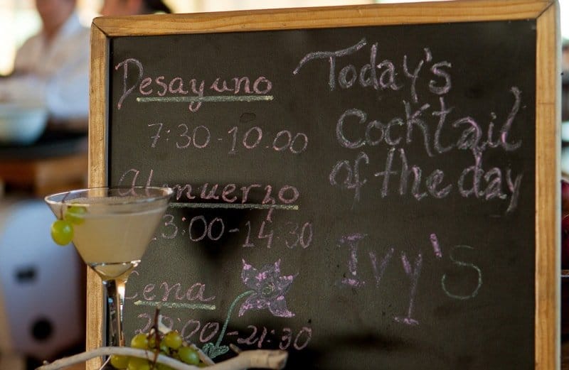 Menu board at Tierra Patagonia's dining room featuring the cocktail of the day and meal times .
